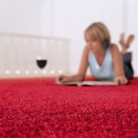 Una donna legge sdraiata su un tappeto